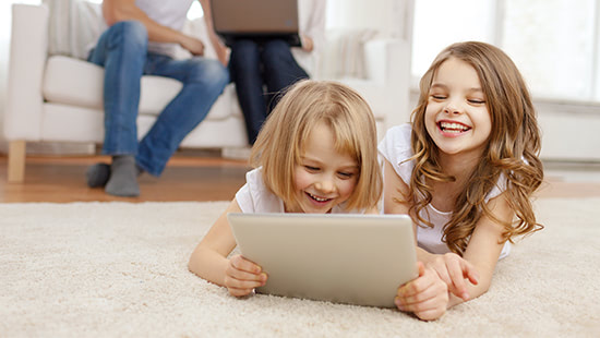children on the floor looking at a tablet