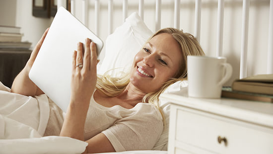 person in bed holding a tablet