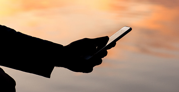 Person holding phone in evening sunset