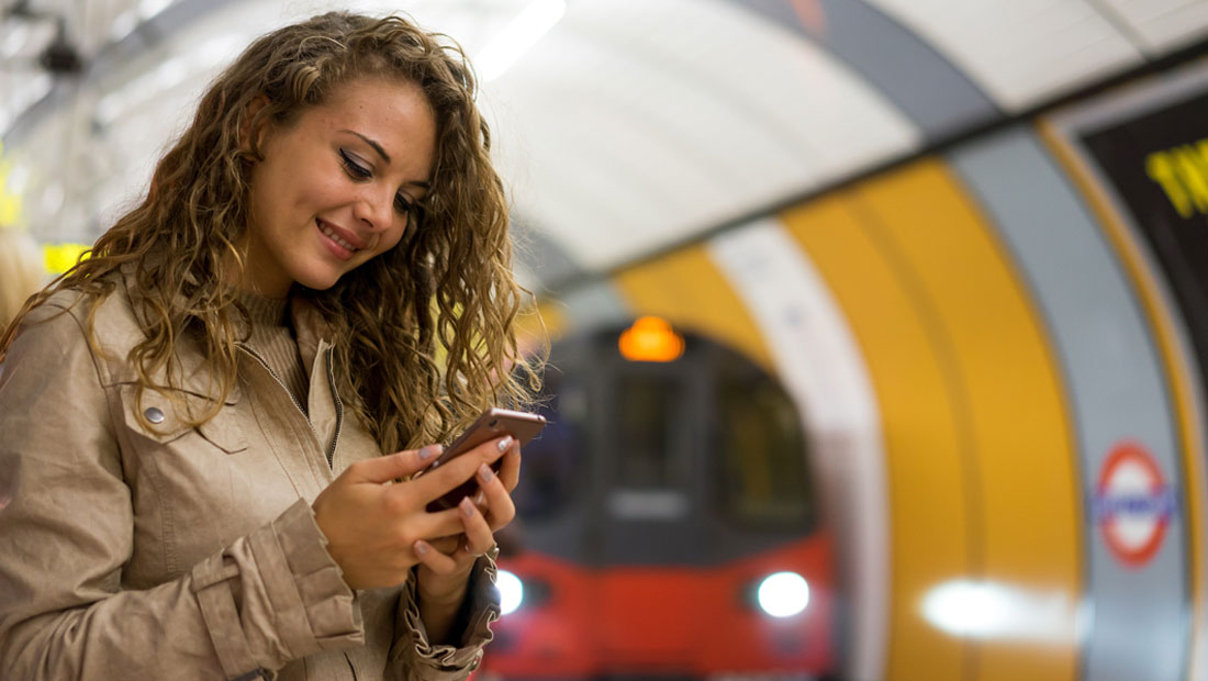 Young woman holding mobile phone on London underground