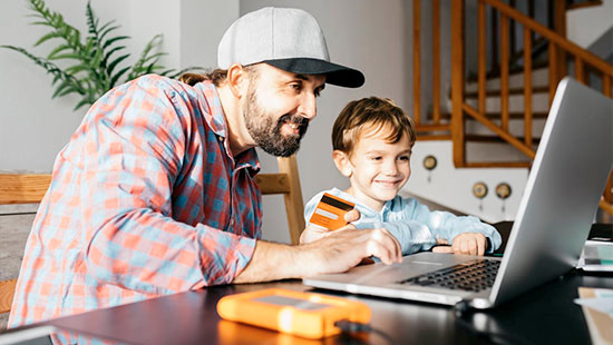 Father and son sitting at laptop buying something online