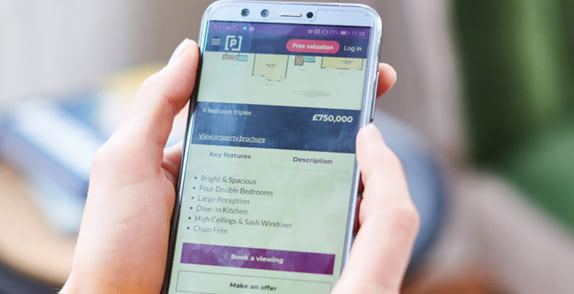 Hands holding smartphone showing Purplebricks website