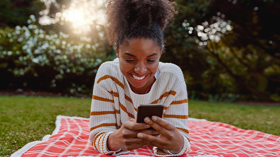 Woman lying on picnic blanket using her phone