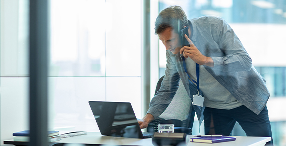 Man in a meeting room using a mobile phone and laptop