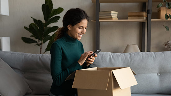 Woman looking at a phone with a parcel on her lap