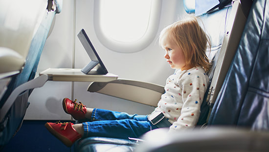 child sitting on a plane with a tablet