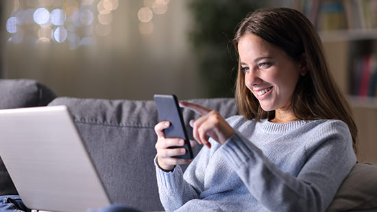 person on a sofa with a laptop and phone