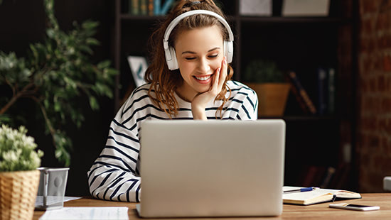person sitting in front of a laptop wearing headphones