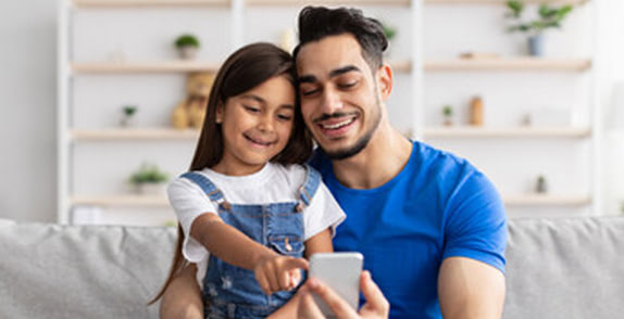 Father and daughter looking at device