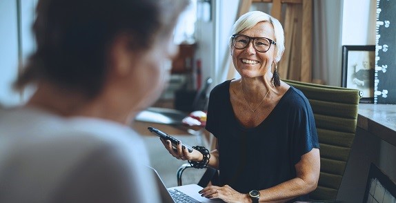 Woman sat on office chair using a laptop and phone