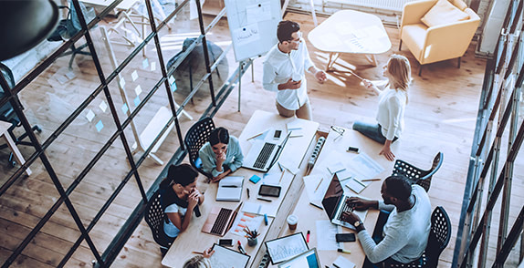 Group of people working together around a large table in an office