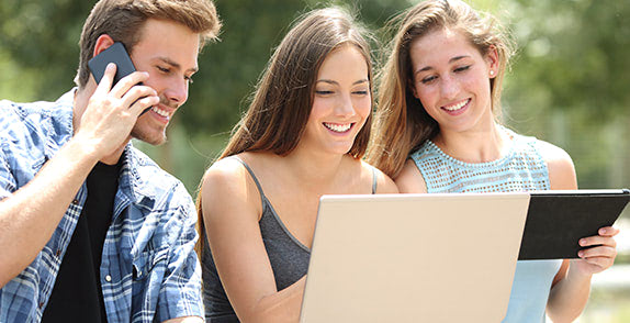 Three people using devices outside