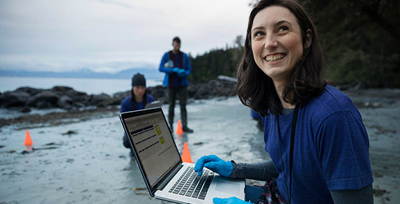 Woman using laptop in the research field on the move