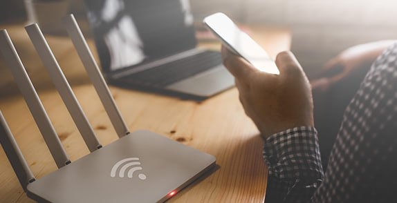 Man handling phone near a router