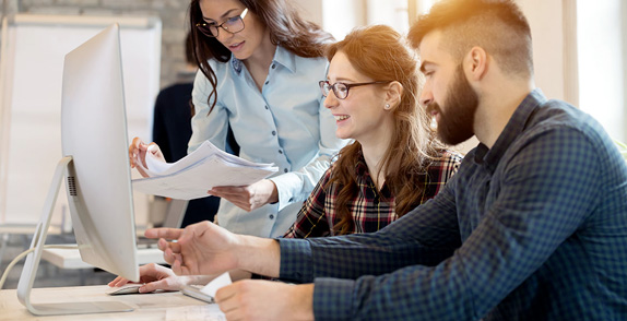 Three people looking at a computer