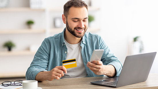 person holding phone near laptop