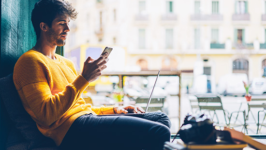 person sitting with phone and laptop