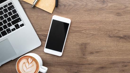phone near laptop and coffee