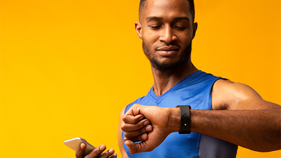 person holding their phone and looking at their smartwatch