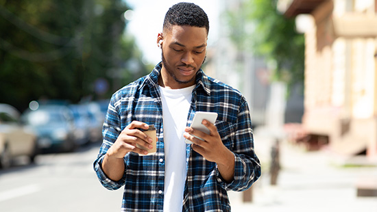 person with coffee holding their phone