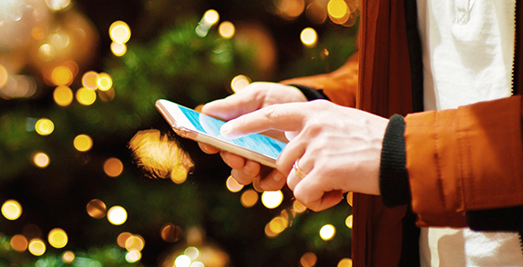 person holding their phone in front of a christmas tree