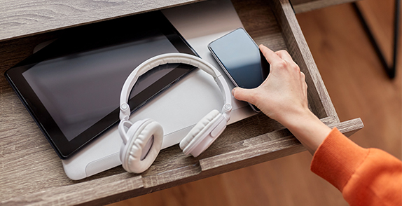 phone, headphones and laptop in a drawer