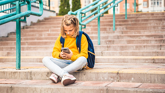 child sitting holding their phone