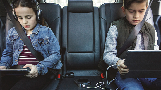 children in a car playing on tablets