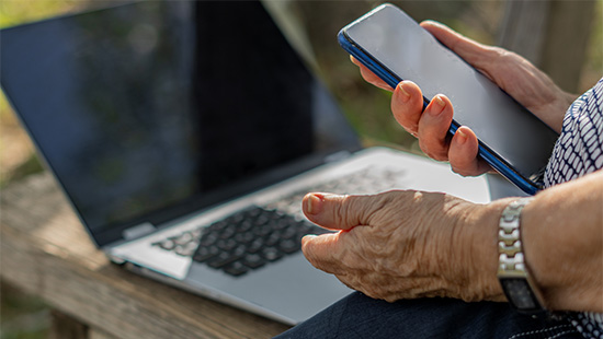 person holding a phone with a laptop