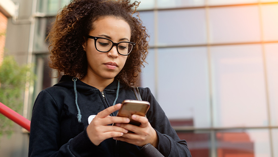 person wearing glasses holding their phone