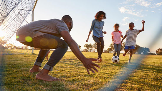 person and children playing football in a field