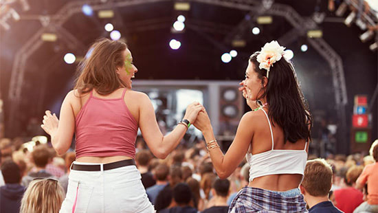 friends holding hands watching a concert