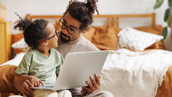 child sitting on a person with a laptop