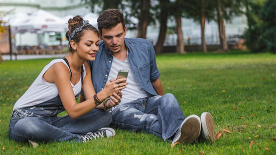 people sitting in a park looking at a phone