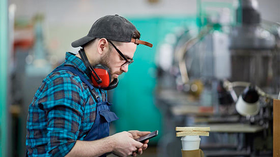 person with headphones round their neck looking at a phone