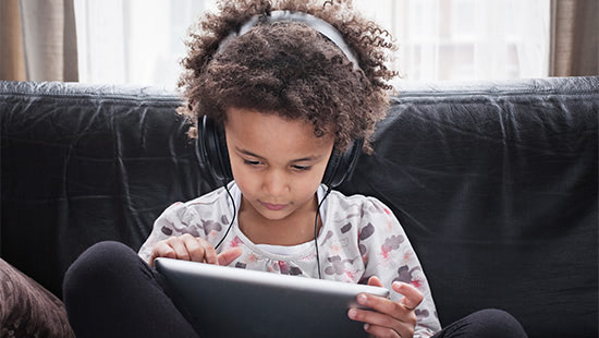 child wearing headphones watching a tablet