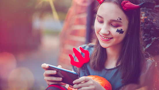 child wearing halloween costume looking at a phone