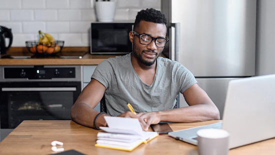 Man sitting at desk with notebook and laptop in front of him